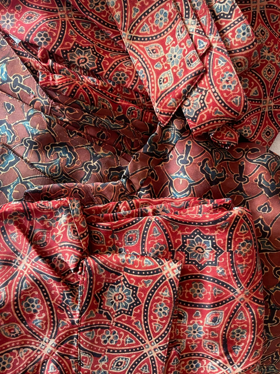 Folded red ajrakh cloth, block-printed medallions in madder, indigo and white