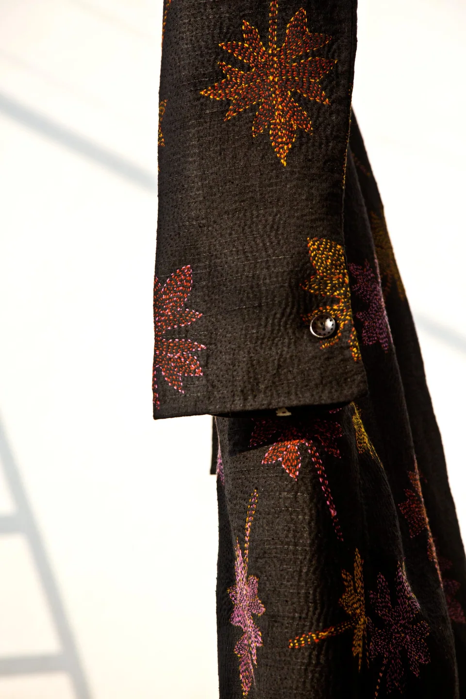 Sleeve of the block-printed kantha coat, flowers worked in rust and pink