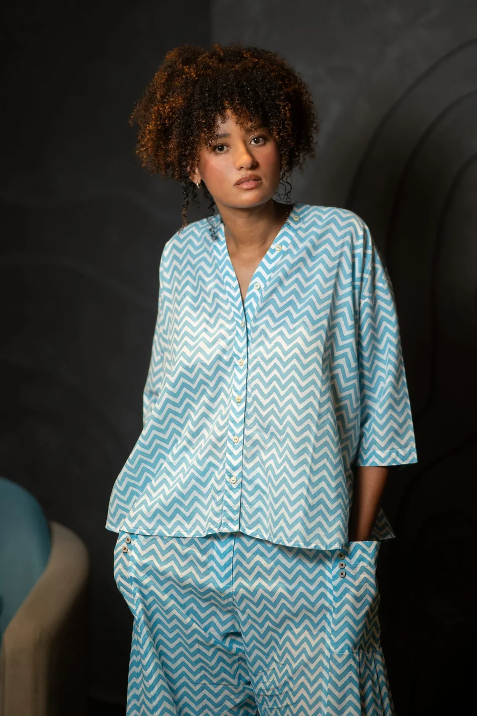 Blue chevron kimono-style top worn with the matching trousers, one hand in a pocket