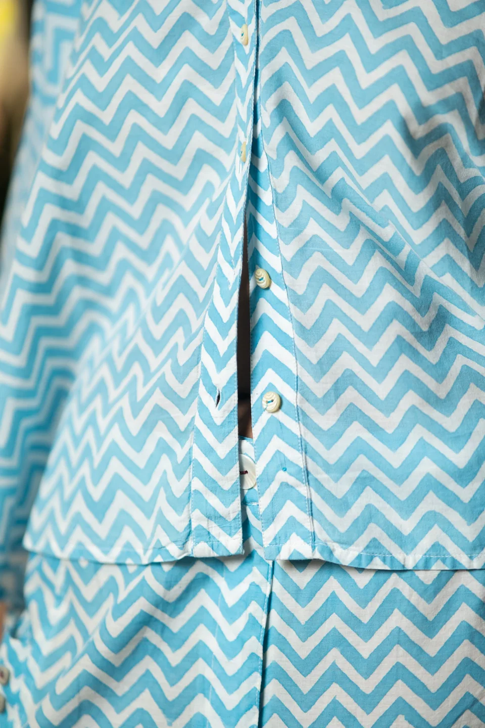 Buttons and hand block-printed chevrons on the placket of the blue top, seen close