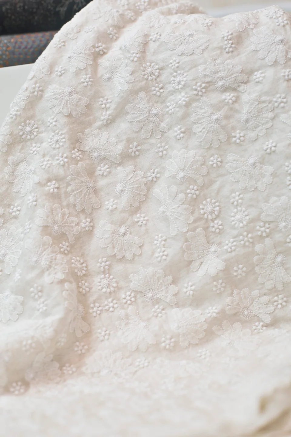White chikankari flowers worked across white cloth, gathered in soft folds