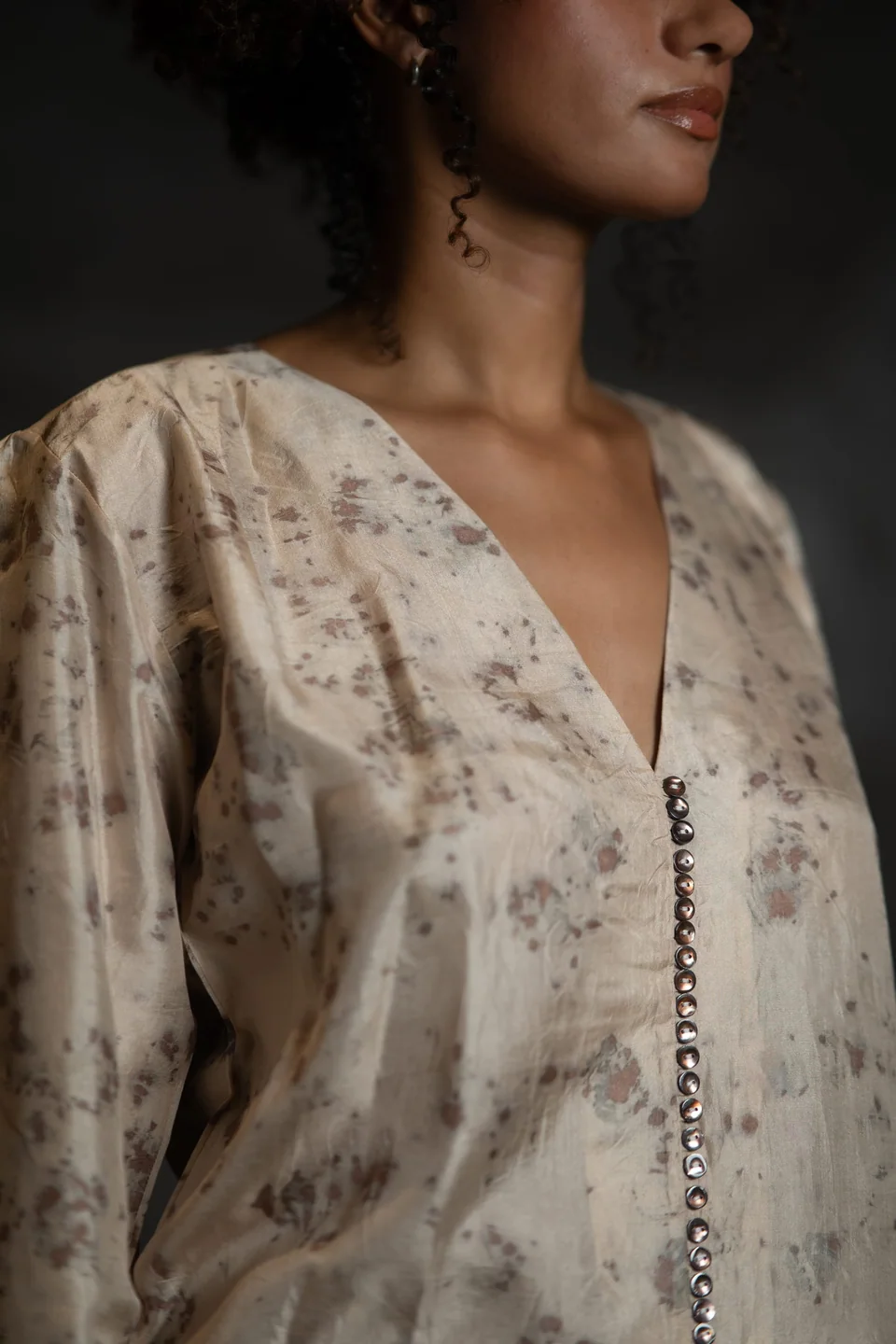 V neckline and a row of small buttons on the eco-printed silk blouse