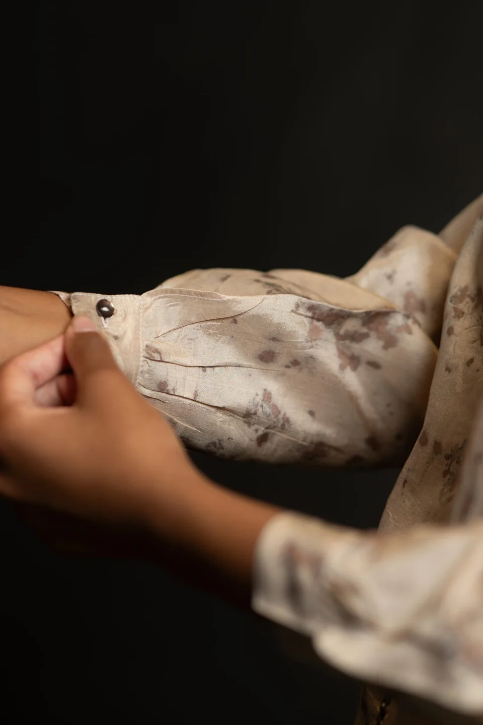 Hands holding an eco-printed silk sleeve, leaf shapes pressed into the cloth