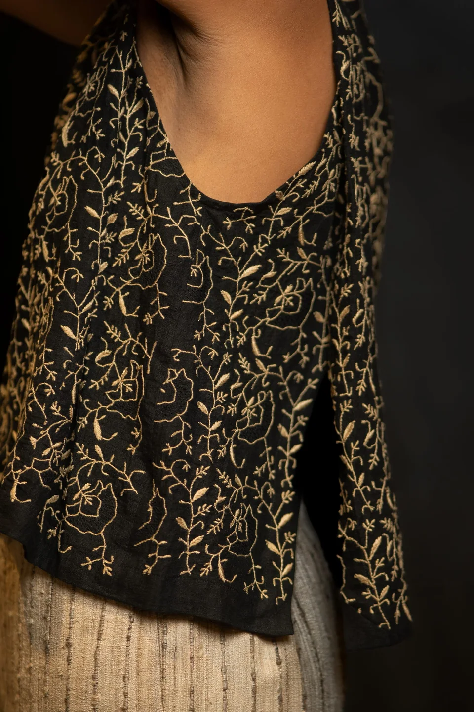 Black vest worked all over in gold hand embroidery, seen from the side