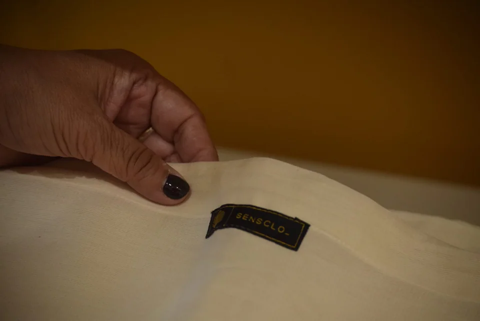 A hand smoothing a Sensclo label onto cream cloth