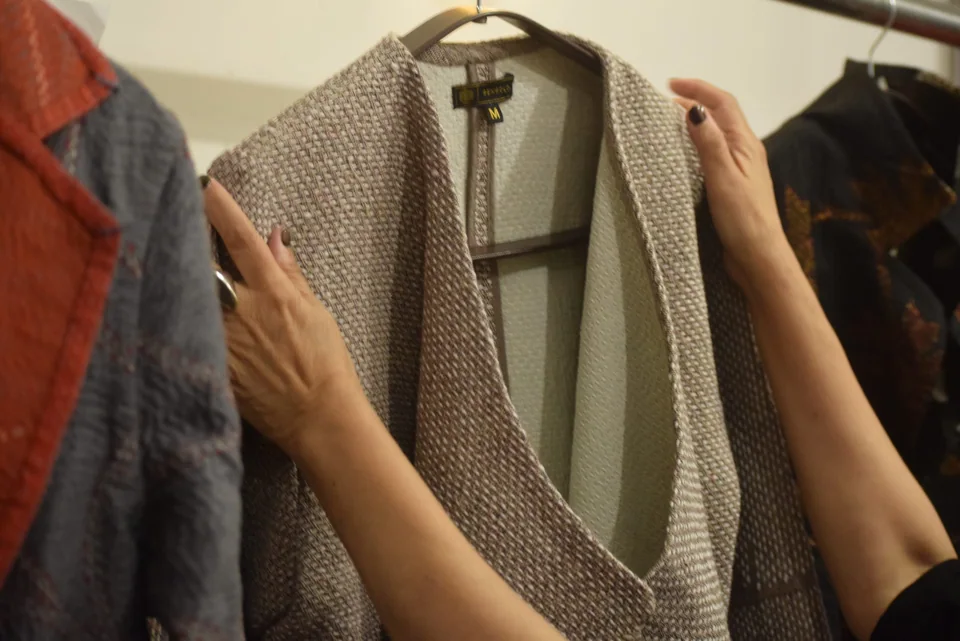 Hands lifting a garment off the studio rail to look at it properly