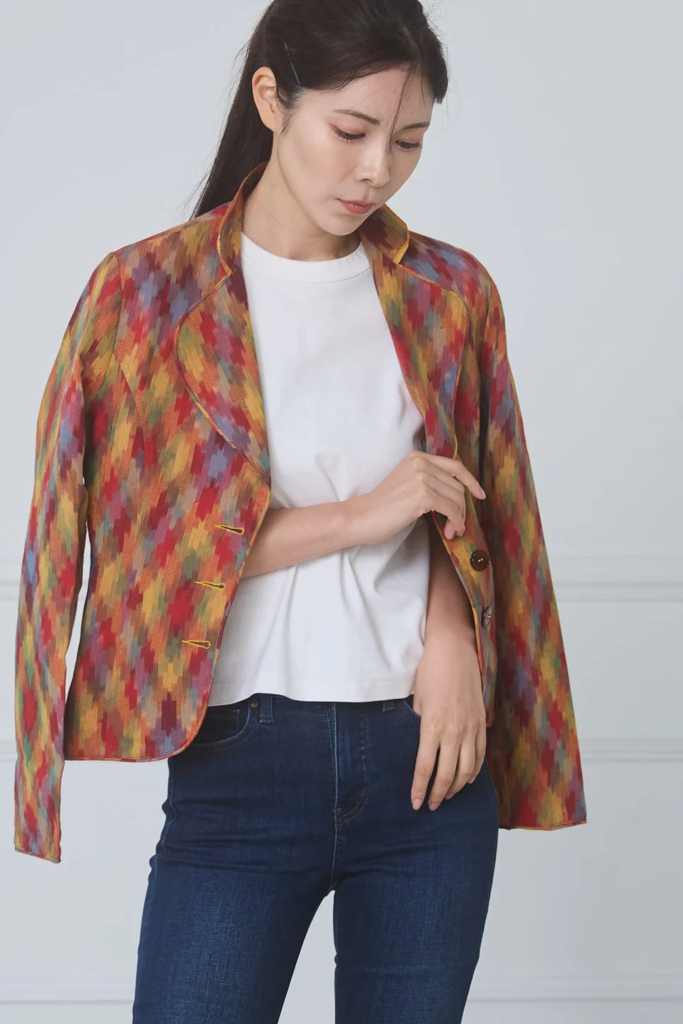 Multicolour double ikat jacket worn open over a white tee and jeans, hand at the lapel