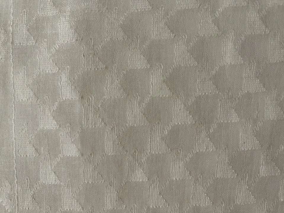 White jamdani seen close, rows of small triangles woven into a sheer white ground