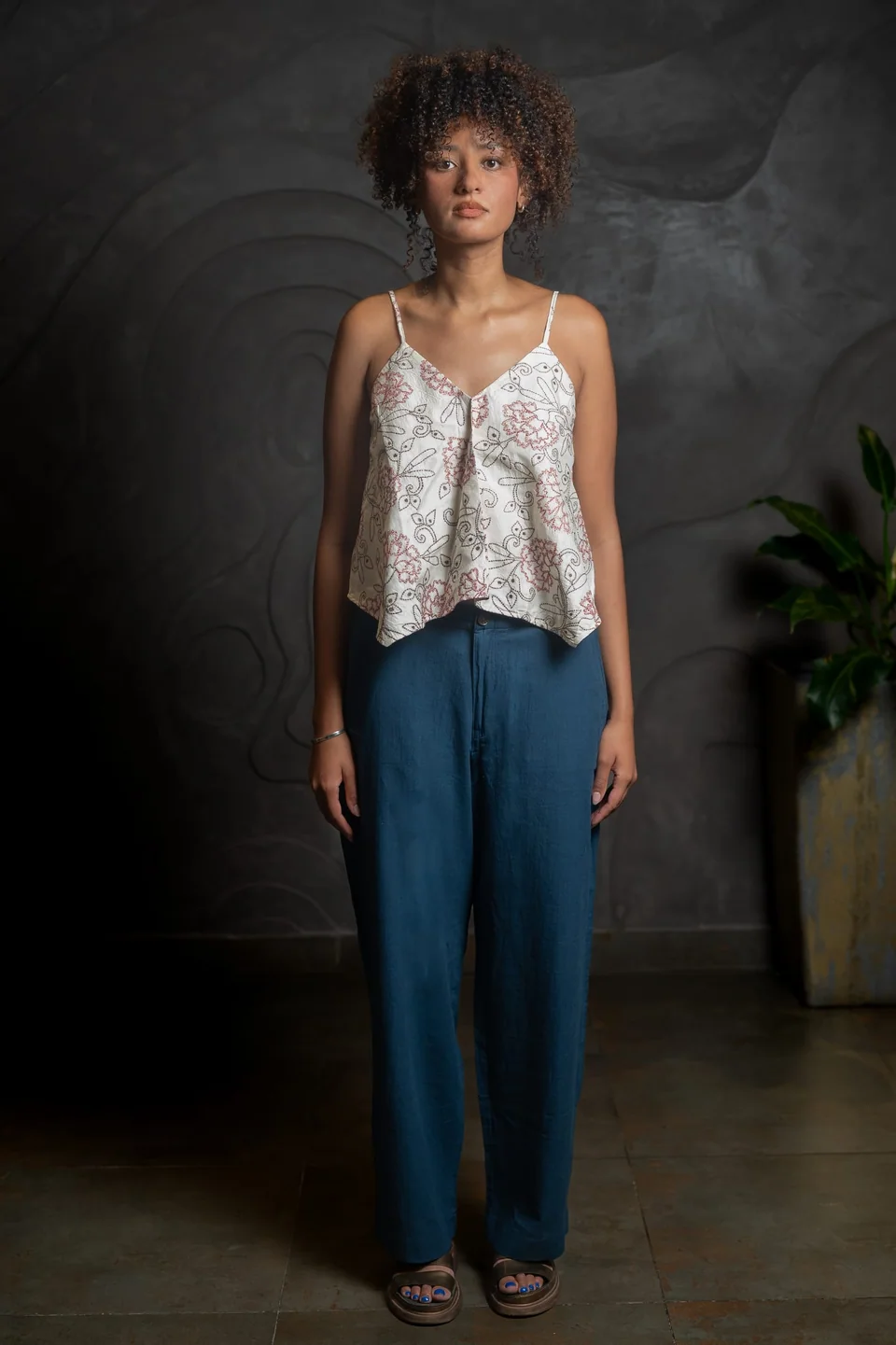 Silk kantha cami with pale floral embroidery worn with teal trousers, hands at the hip