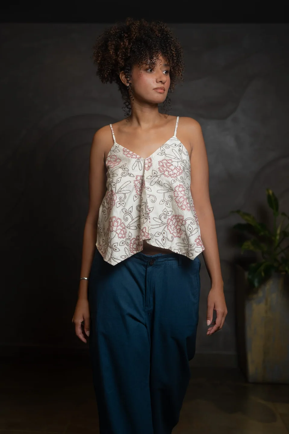 Silk kantha cami worn with teal trousers, one hand raised to the hair