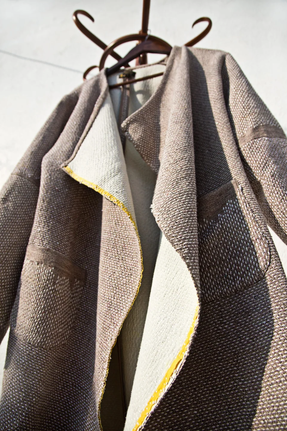 Lapel of the grey kantha shawl coat with a yellow edge showing