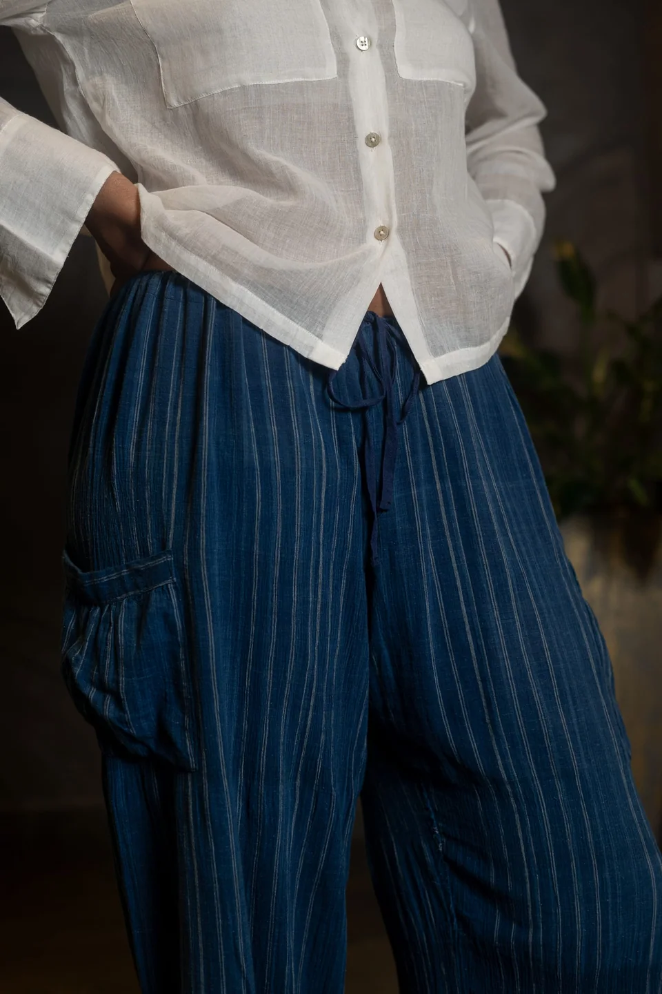 Unbleached cotton shirt worn with indigo handloom trousers, standing in daylight