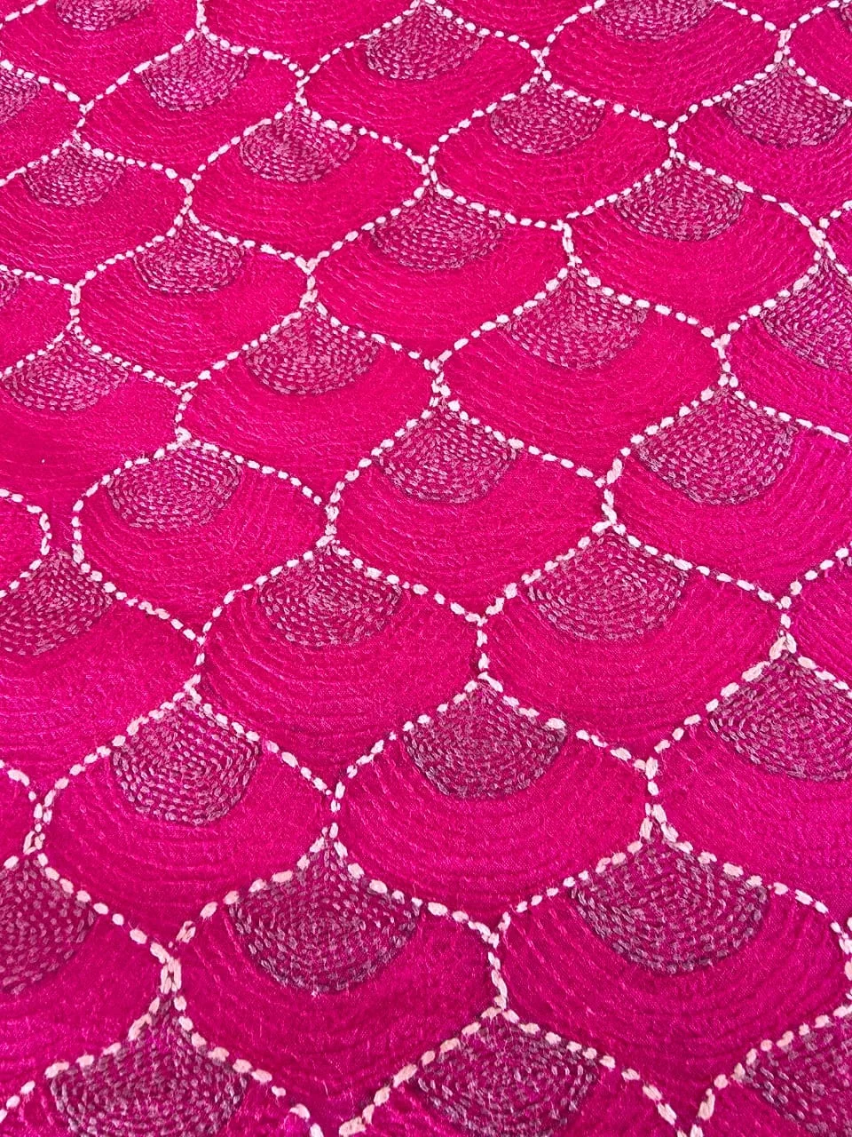 Magenta cloth covered in white kantha stitching worked in a scallop repeat