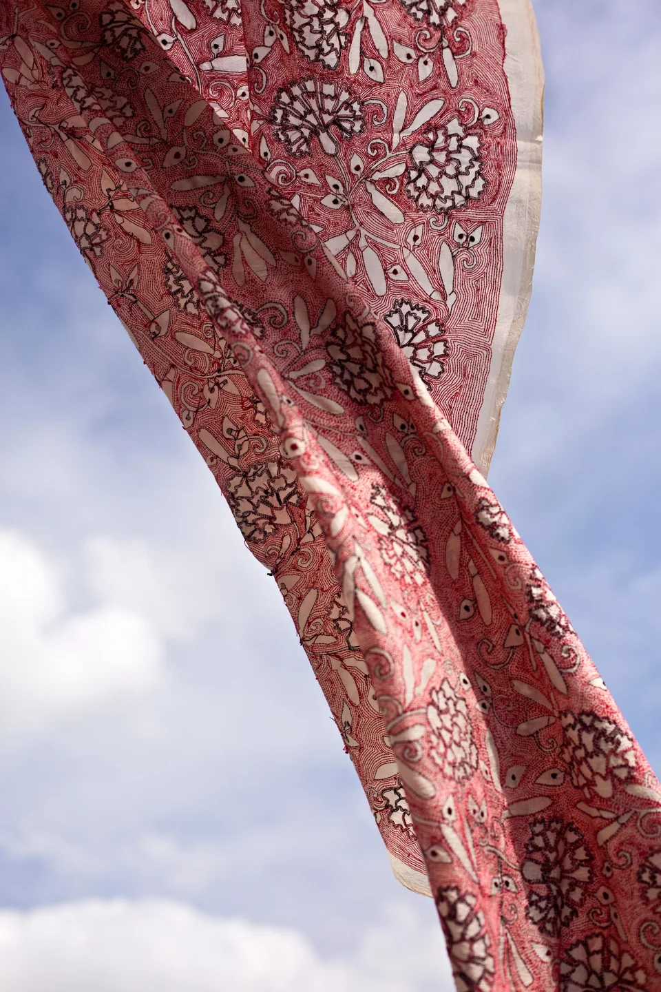 Red and white cloth lifted against an open sky