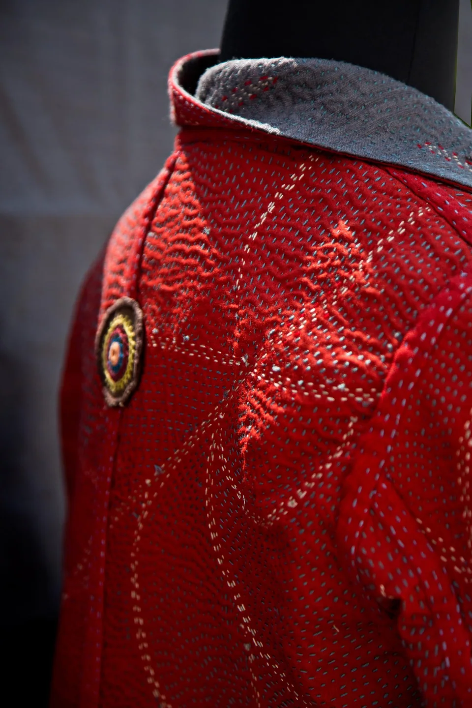 Collar and round button of the red kantha coat, running stitch worked in long curves