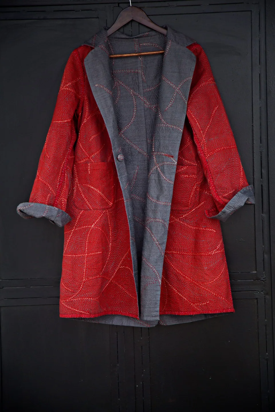 The red and grey reversible kantha coat hanging, red side out