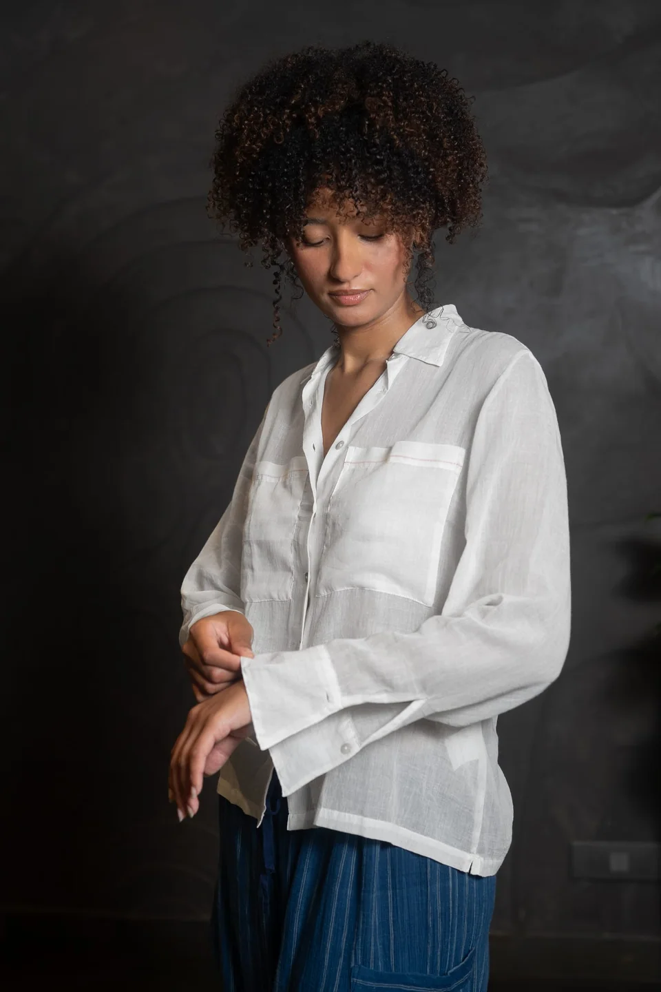 Looking down at the long cuffs of the sheer muslin shirt