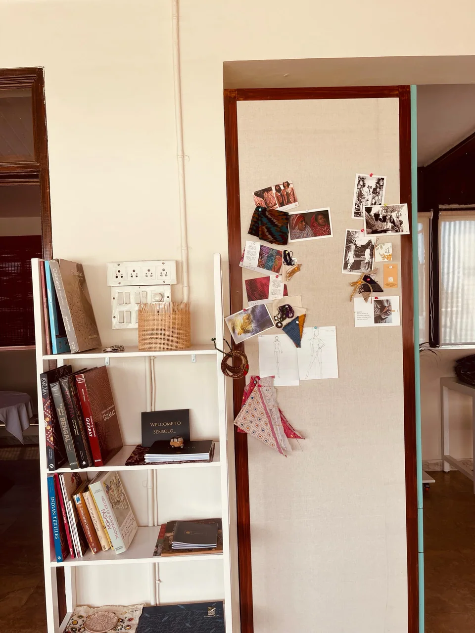 A bookshelf and a pinboard of photographs and swatches at the studio