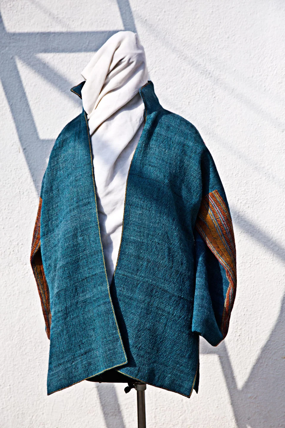 Teal handwoven jacket on a stand in the sun