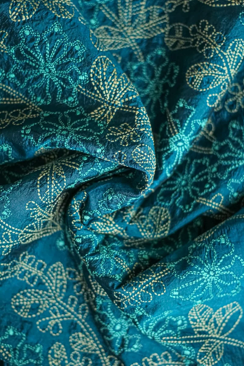 Teal cloth with white kantha flowers worked across it