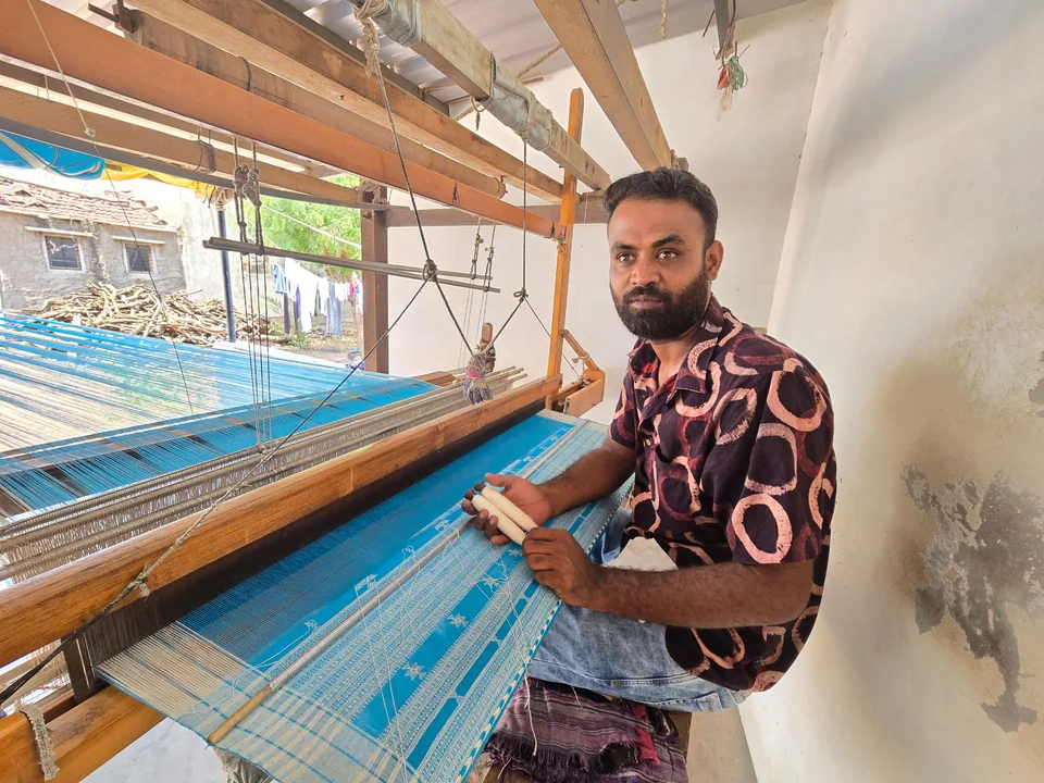 A weaver working at the loom on a bright blue warp