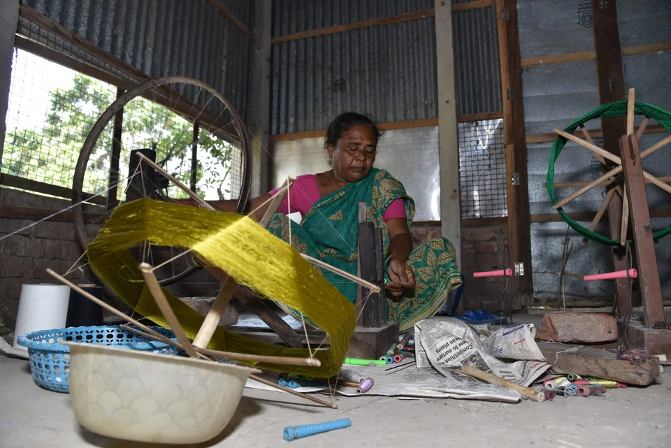 A weaver winding yellow silk yarn at home in Fulia, Bengal