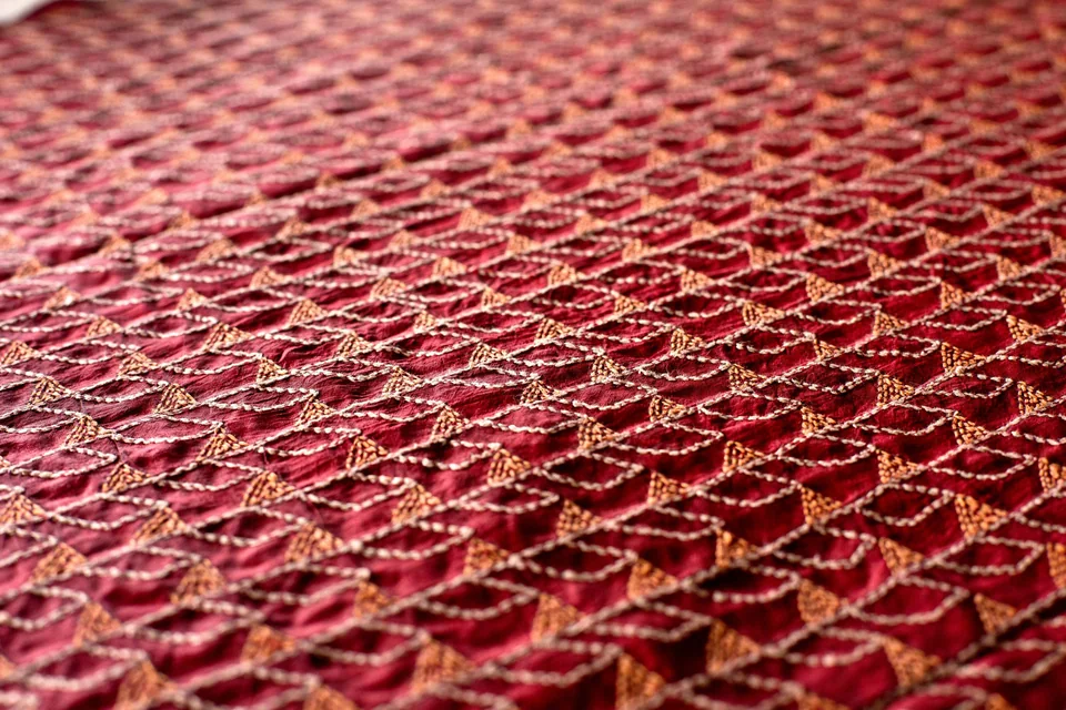 Wine-coloured kantha, rows of running stitch catching the light