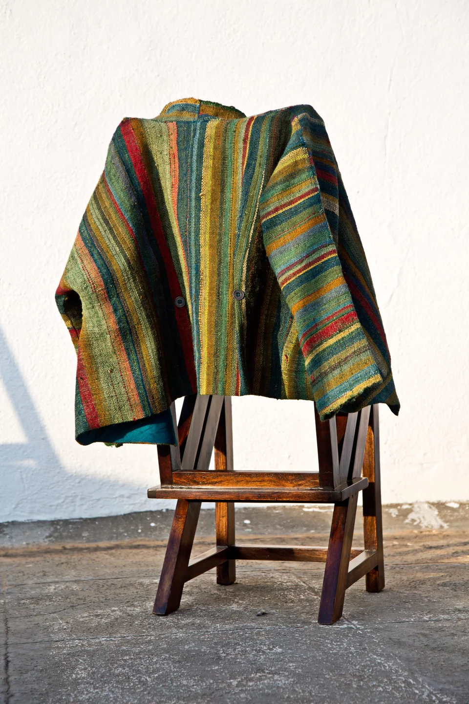 The handwoven wool jacket laid over a wooden chair